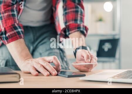 Freelancer Online-Shopping mit Smartphone-App und Kreditkarte aus dem Home Office des kleinen Unternehmens, selektiver Fokus Stockfoto