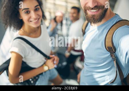 Lächelnde afrikanische junge Dame, die in der Nähe des bärtigen Mannes steht Die bewegliche Treppe Stockfoto