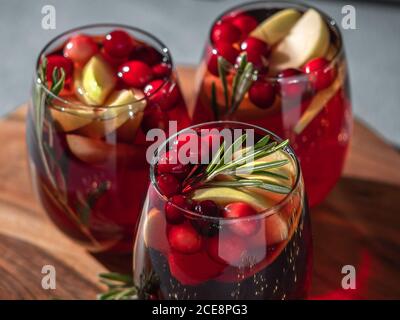 Wintersangria auf der Tischplatte. Drei Gläser Sangria mit Fruchtscheibe, Cranberry und Rosmarin Stockfoto
