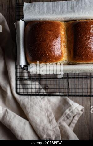 Blick von oben auf frisch gebackene Burger-Brötchen auf Metall Gitter mit Backpapier auf Tisch Stockfoto