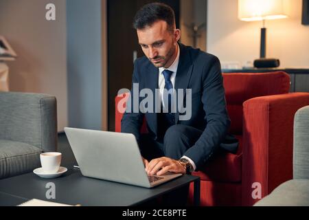 Ernster Mann, der sich auf das Geschäftsmeeting vorbereitet und sein verwendet Gadget Stockfoto