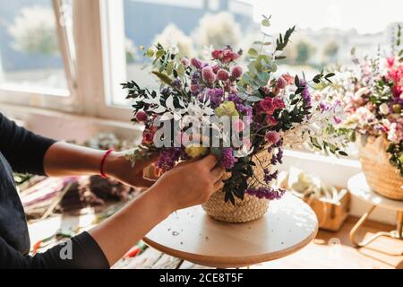 Ernte der Seitenansicht der weiblichen Designerin Anordnung dekorative Blüte Blumensträuße während der Arbeit auf Bestellung für die Veranstaltung in kreativen Floristik studio Stockfoto