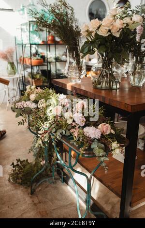 Zarte Hochzeit florale Komposition mit blühenden rosa Rosen auf angeordnet Metallständer neben Regal mit verschiedenen Blumensträuße in Floristik speichern Stockfoto