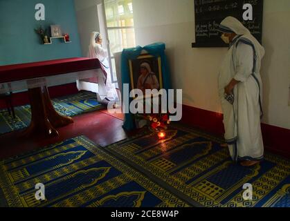 Katholische Nonnen aus Nirmala Shishu Bhavan reinigen das Foto von Mutter Teresa und bereiten den Ort zum Gebet vor, um an den 110. Geburtstag von Mutter Teresa zu erinnern. Agartala, Tripura, Indien. Stockfoto