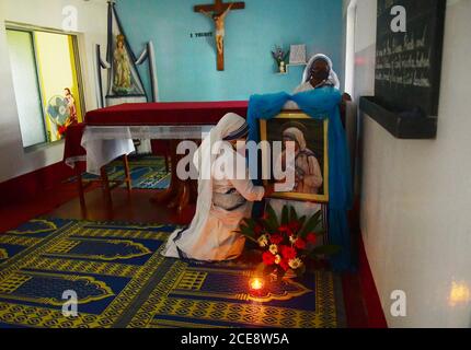 Katholische Nonnen aus Nirmala Shishu Bhavan reinigen das Foto von Mutter Teresa und bereiten den Ort zum Gebet vor, um an den 110. Geburtstag von Mutter Teresa zu erinnern. Agartala, Tripura, Indien. Stockfoto