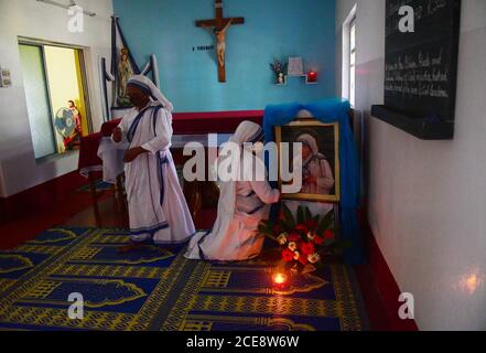 Katholische Nonnen aus Nirmala Shishu Bhavan reinigen das Foto von Mutter Teresa und bereiten den Ort zum Gebet vor, um an den 110. Geburtstag von Mutter Teresa zu erinnern. Agartala, Tripura, Indien. Stockfoto