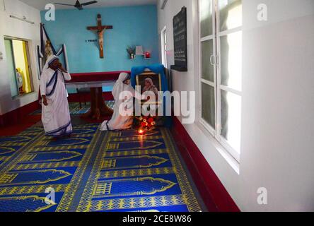 Katholische Nonnen aus Nirmala Shishu Bhavan reinigen das Foto von Mutter Teresa und bereiten den Ort zum Gebet vor, um an den 110. Geburtstag von Mutter Teresa zu erinnern. Agartala, Tripura, Indien. Stockfoto