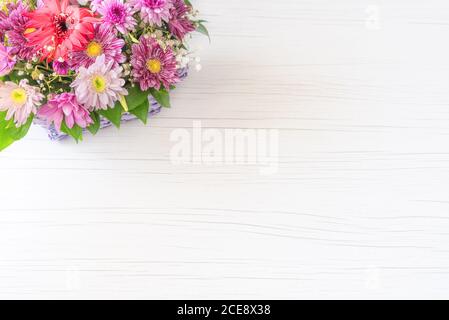 Schöner Strauß von hellen Blumen im Korb auf weißem Holzhintergrund. Stockfoto