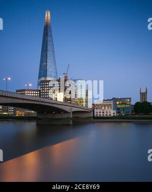 Der Shard dominiert den Blick auf die Skyline von London während der Blauen Stunde auf einer völlig klaren Sommer Abend als die Themse fließt von unten. Stockfoto