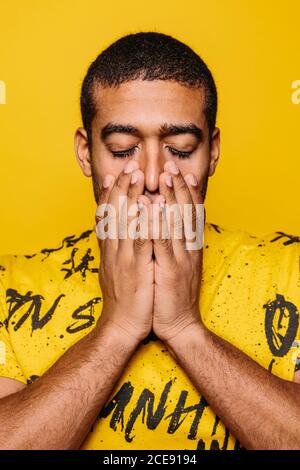 Gemischter junger Mann, der mit ernstem Ausdruck auf die Kamera schaut Auf gelbem Hintergrund Stockfoto