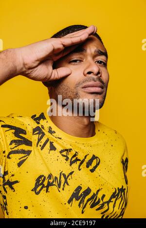 Gemischter junger Mann, der mit ernstem Ausdruck auf die Kamera schaut Auf gelbem Hintergrund Stockfoto