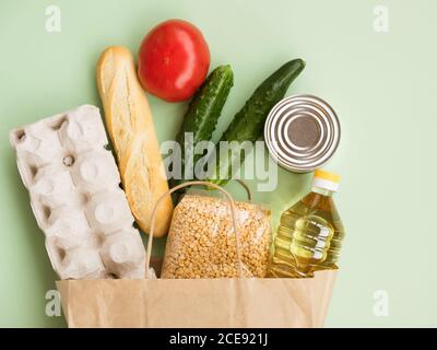 Essen in einem Papierbeutel: Eier, Gurke, Öl, Tomaten und Baguette auf gelbem Hintergrund Stockfoto