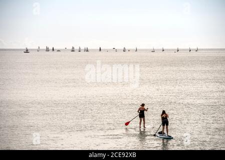 Shoreham 31. August 2020: Zwei Tretboarder und einige Segler in den Dighies genießen die flachen ruhigen Bedingungen in Shoreham-by-Sea vor der Küste in West Sussex am Feiertagsmontag. Kredit: Andrew Hasson/Alamy Live Nachrichten Stockfoto