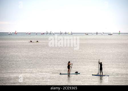 Shoreham 31. August 2020: Zwei Tretboarder und einige Segler in den Dighies genießen die flachen ruhigen Bedingungen in Shoreham-by-Sea vor der Küste in West Sussex am Feiertagsmontag. Kredit: Andrew Hasson/Alamy Live Nachrichten Stockfoto