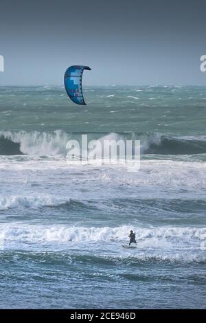 Ein einsamer Kitesurfer, der den starken Wind von Storm Jorge in Fistral in Newquay in Cornwall genießt. Stockfoto