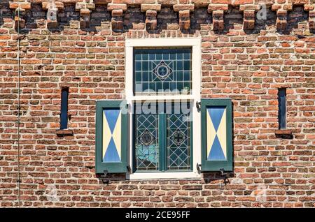 Hattem, Niederlande, 31. Juli 2020: Teil der Fassade des Dijkpoort (Deichtor), mit einem kleinen Buntglasfenster mit hölzernen Fensterläden in a b Stockfoto