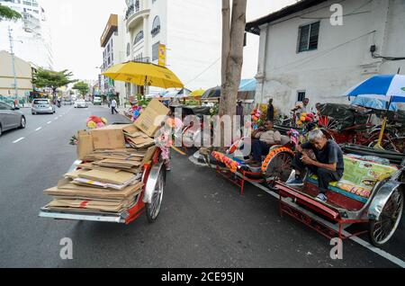 Georgetown, Penang/Malaysia - 27 2016. August: Rikscha-Fahrer rasten auf der Straße. Stockfoto