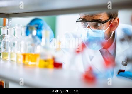Junge Forscher mit Schutzbrille Prüfung Reagenzgläser in der Labor Stockfoto