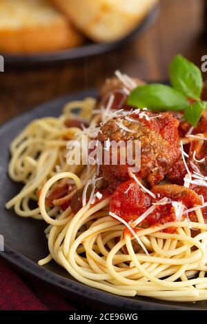 Spaghetti und Fleischbällchen mit Tomatensauce und Parmesankäse Ein schwarzer Essteller Stockfoto