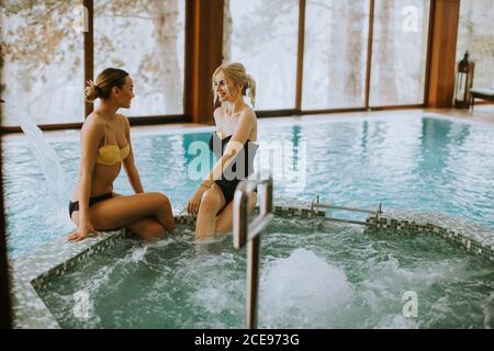 Hübsche junge Frauen sitzen und entspannen an der Whirlpool-Badewanne Stockfoto