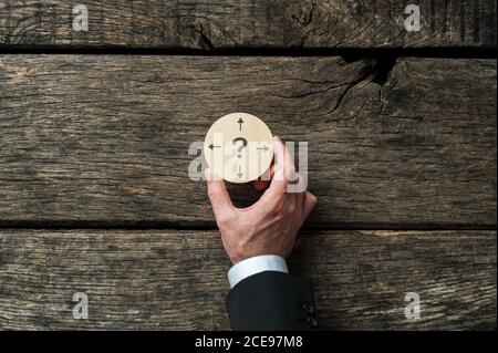 Geschäftsplanung und Entscheidung konzeptionelles Bild - Geschäftsmann hält Holz Schneiden Sie den Kreis mit Fragezeichen und Pfeilen, die in verschiedene zeigen Anweisungen Stockfoto