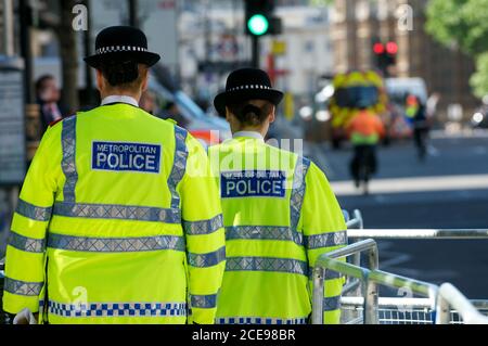 London, England - 25. Mai 2011: Zwei Polizeifrauen gehen die Straße entlang zwei Polizeifrauen gehen die Straße entlang in fluoreszierenden Jacken Stockfoto