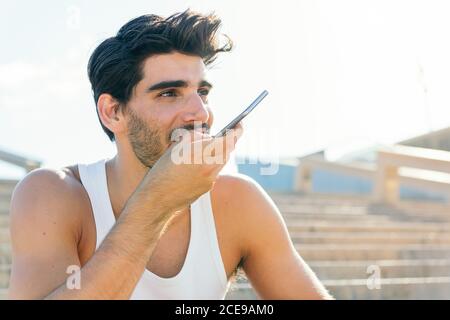 Schöner Sportler in einem Tank Top Aufnahme einer Sprachnachricht auf seinem Telefon, Technologie und gesunde Lebensweise Konzept, kopieren Platz für Text Stockfoto