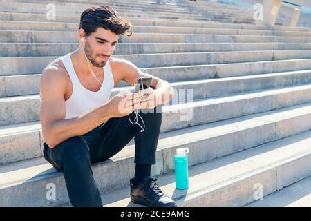 Sportler mit Kopfhörer wählt Musik auf seinem Telefon, um während seines Trainings zu hören, urbanes Sportkonzept und gesunden Lebensstil, Kopierraum für Text Stockfoto