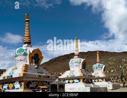 Buddhistische Stupas mit Gebetsfahnen über schneebedeckten Himalaya unter blauem Himmel zwischen Manali und Kaza, Himachal Pradesh, Indien. Stockfoto