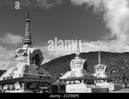 Buddhistische Stupas mit Gebetsfahnen über schneebedeckten Himalaya unter blauem Himmel zwischen Manali und Kaza, Himachal Pradesh, Indien. Stockfoto