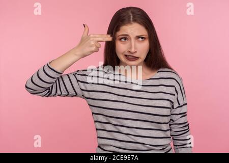 Bitte tötet mich! Porträt einer verzweifelten Frau in gestreiftem Sweatshirt mit Fingergun zum Kopf, schießen sich selbst, Selbstmord Geste, um Depres zu stoppen Stockfoto