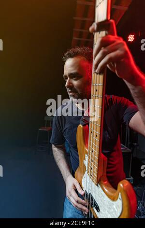 Der kaukasische Mann ist auf der Bühne zu sehen. Handsome Male Person spielt auf Bass Gitarre bei Concert. Stockfoto