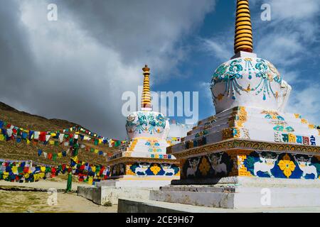 Buddhistische Stupas mit Gebetsfahnen über schneebedeckten Himalaya unter blauem Himmel zwischen Manali und Kaza, Himachal Pradesh, Indien. Stockfoto