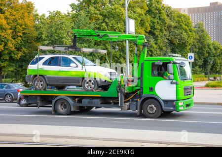 Abschleppen des Fahrzeugs auf dem Gabelstapler. Abschleppwagen mit ausgerüsteter Aufhängung Kranevakuierung und Transport zu einem feinen Parkplatz Stockfoto