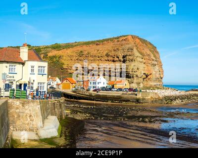 Vor dem Cod and Lobster Pub am Hafen Im Staithes North Yorkshire im Hochsommer Blick auf Cowbar nab Stockfoto