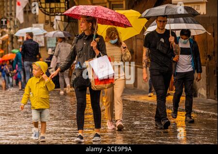 Florenz, Italien. August 2020. Der Regen fällt nach einer sehr heißen Woche und überall sind Sonnenschirme draußen, wenn die Leute über die Ponte Vecchio fahren - Masken bleiben optional. Besucher kehren zurück, um die verschiedenen Sehenswürdigkeiten der historischen Stadt Florenz nach der Lockerung des Coronavirus (covid 19) Reisebeschränkungen zu sehen. Kredit: Guy Bell/Alamy Live Nachrichten Stockfoto