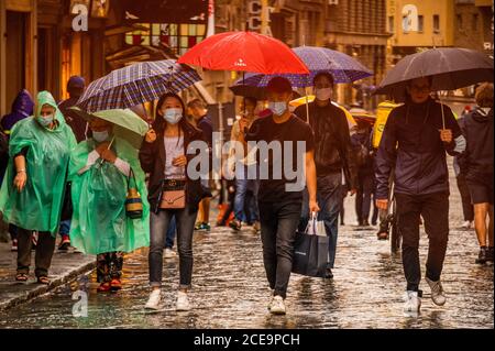 Florenz, Italien. August 2020. Der Regen fällt nach einer sehr heißen Woche und überall sind Sonnenschirme draußen, wenn die Leute über die Ponte Vecchio fahren - Masken bleiben optional. Besucher kehren zurück, um die verschiedenen Sehenswürdigkeiten der historischen Stadt Florenz nach der Lockerung des Coronavirus (covid 19) Reisebeschränkungen zu sehen. Kredit: Guy Bell/Alamy Live Nachrichten Stockfoto