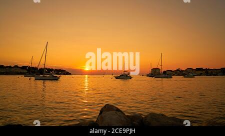 Sonnenuntergang mit Schiffen, die in der Hafenstadt Porec in Istrien in Kroatien Stockfoto