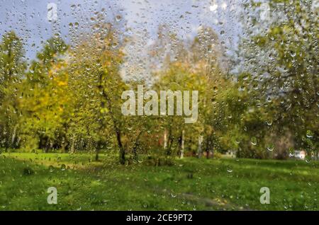 Heller Herbst verschwommen Landschaft nach Regen durch nasse Fenster Glas Stockfoto