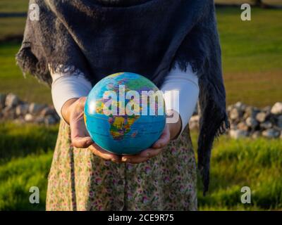 Eine Frau mit einem Ball der Welt oder den Planeten Erde in seiner Hand. Ökologiekonzept Stockfoto