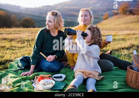 Kleines Mädchen mit Mutter und Großmutter, Picknick in der Natur, mit Fernglas. Stockfoto