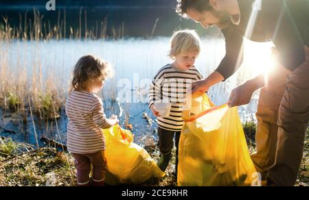 Vater mit kleinen Kindern sammeln Müll im Freien in der Natur, plogging Konzept. Stockfoto