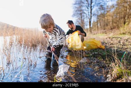 Vater mit kleinen Sohn sammeln Müll im Freien in der Natur, plogging Konzept. Stockfoto