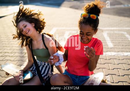 Teenager Mädchen Freunde mit Skateboards sitzen im Freien in der Stadt. Stockfoto