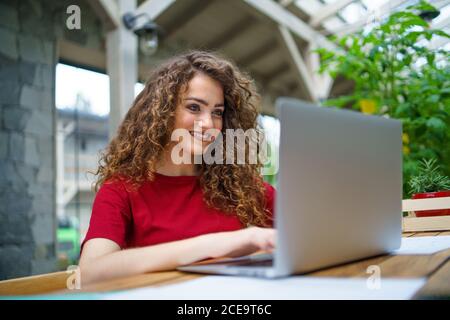 Junge Frau sitzt drinnen im Büro, mit Laptop. Stockfoto