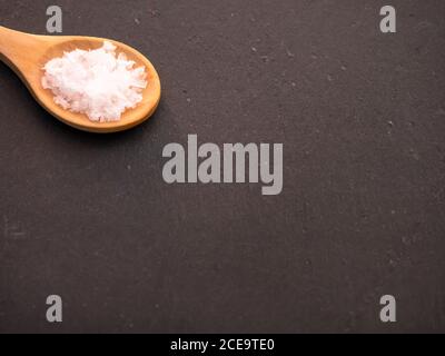 Löffel aus Holz mit Salz Blume Flocken auf einer Schiefertafel Platte Stockfoto