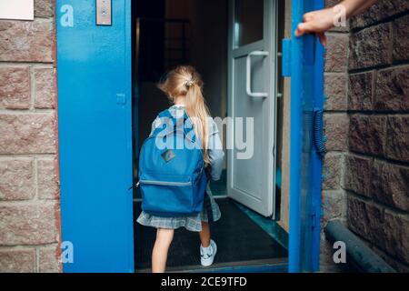 Rückansicht des Vaters, der von der Schule nach Hause kommt Mit seiner Tochter, die Rucksack trägt Stockfoto