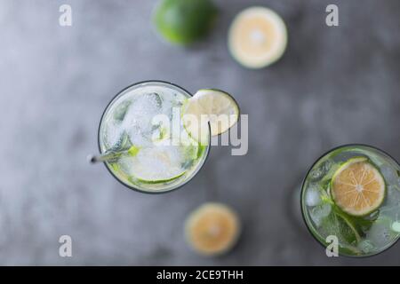 Flach Lay Top-Ansicht der kalten erfrischenden Getränk mit Scheiben Limettenrippen und Eis Reverse-Light-Bild im Studio mit Weiß beleuchteter Hintergrund
