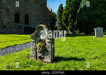 Altes abgenutztes Grab mit Schädel und Kreuzknochen im Dorfkirchenhof, Humbie Parish Church, East Lothian, Schottland, Großbritannien Stockfoto