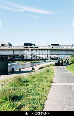 Eine Gruppe von Leuten, die auf einem Bürgersteig unter der Brücke gehen. Vertikale Außenaufnahme. Stockfoto